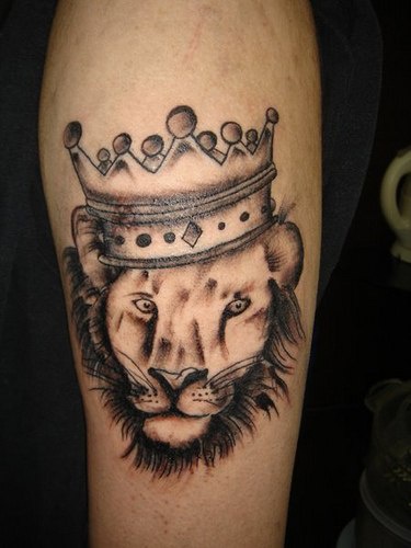 El tatuaje de la cabeza de un leon coronado con una corona en color negro