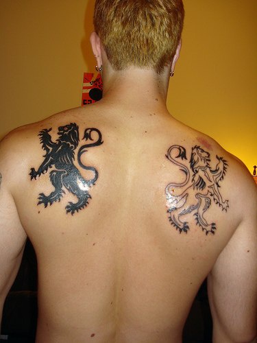 los tatuajes simetricos blanco y otro negro de dos leones heraldicos en la espalda