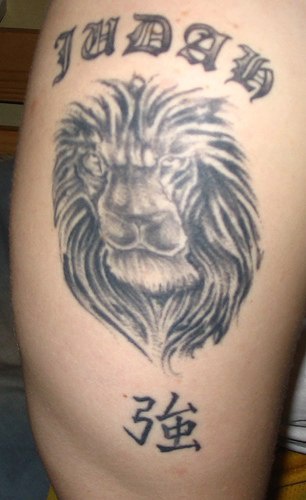 El tatuaje de la cabeza de un leon judah con unos jeroglificos en color negro