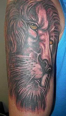 El tatuaje en el brazo de la cabeza de un leon con ojos de color