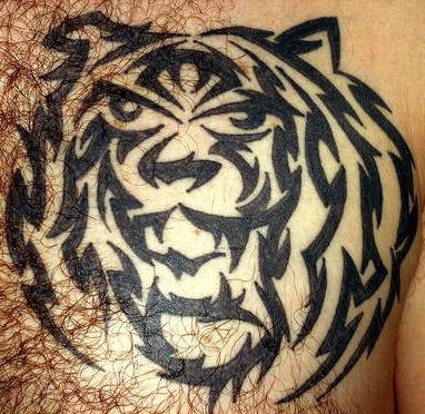El tatuaje tribal de la cabeza de un tigre en negro hecho en el pecho