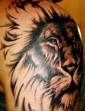 El tatuaje de la cabeza de un león hermoso con ojos de color en el hombro