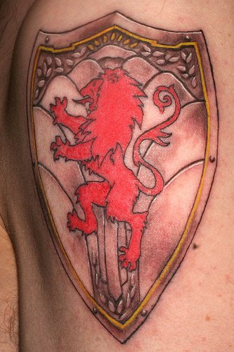 El tatuaje heraldico de un leon rojo encima de un escudo de acero