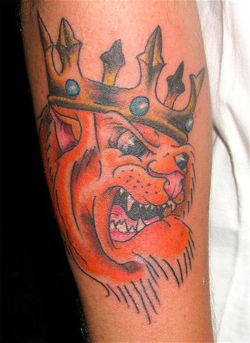 El tatuaje de la cabeza de un leon enojado con una corona hecho al estilo caricatura