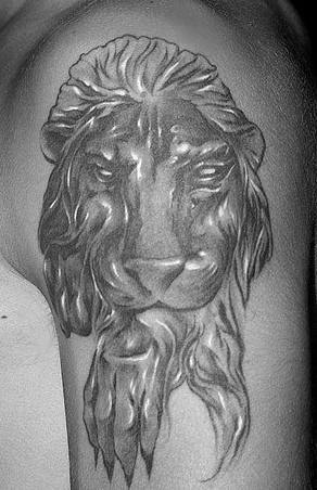 El tatuaje de la cabeza de un leon negro lambiendo su pata hecho en el brazo