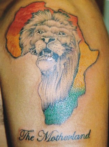 El tatuaje del continente africa de color con la cabeza de un leon y letras &quotla madre patria"