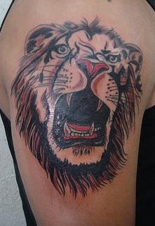 El tatuaje de la cabeza de un leon rugiendo en color en el brazo o hombro