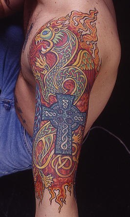 El tatuaje asiatico en color de un dragon con alas y una cruz azul en el brazo o hombro
