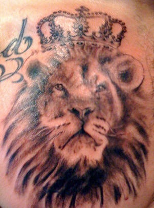 El tatuaje de la cabeza de un leon con una corona hecho con tinta negra