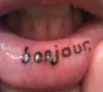 Tatuaggio sul labbro &quotBONJOUR" a lettere minuscole