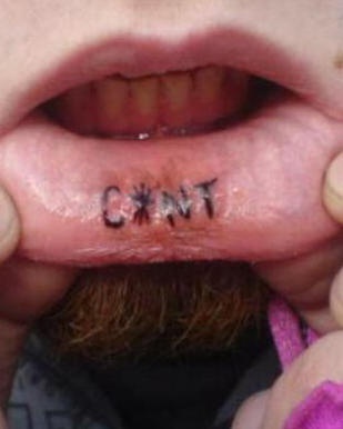 Tatuaggio sul labbro &quotC*NT" a lettere grandi