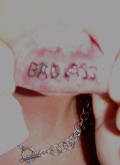 Tatuaggio sul labbro &quotBAD ASS" a lettere rosse grandi