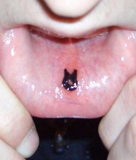Le tatouage de petit noir signe rond sur la lèvre