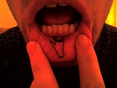 Tattoo mit coolem Rocker Handzeichen an der Lippe