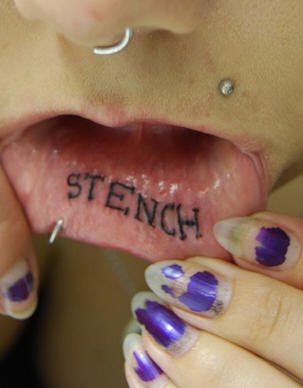 Le tatouage de mot stench à gos lettres simples sur la  lèvre