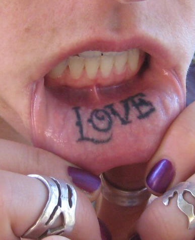 Schön stilisiertes Tattoo &quotLove" an der Lippe