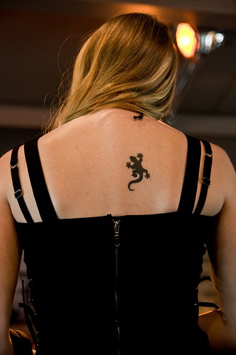 El tatuaje pequeño de una lagartija de color negro en la espalda