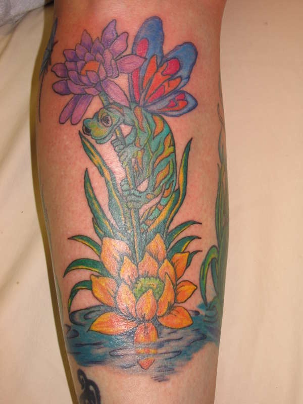 El tatuaje de una lagartija en unos flores en el agua hecho en color