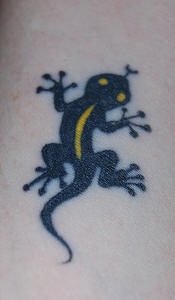 El tatuaje pequeño de una lagartija de color negro con amarillo