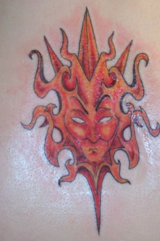 Red tribal sun deity tattoo