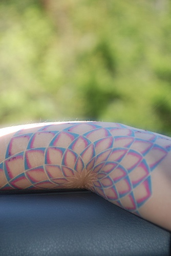 el tatuaje surrealista de una flor de loto hecho en color en el brazo