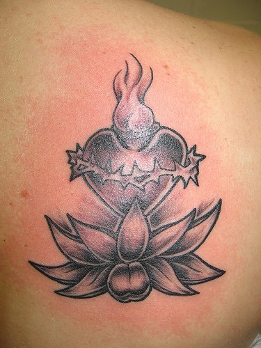 el tatuaje de una flor de loto con el corazon sagrado hecho en color negro