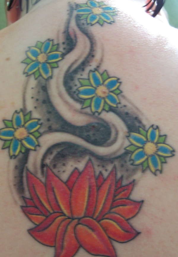 el tatuaje de una flor de loto roja y otras flores hecho en la espalda