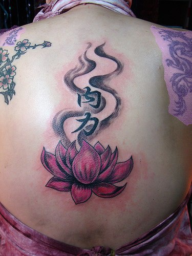 el tatuaje de una flor de loto con jeroglificos en la espalda