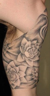 el tatuaje de las flores de loto en color negro hecho en el brazo