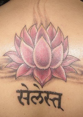 el tatuaje de una flor de loto de color rosa con el escrito en hindu hecho en la espalda