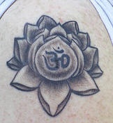 el tatuaje de una flor de loto con una mantra om adentro hecho en color negro