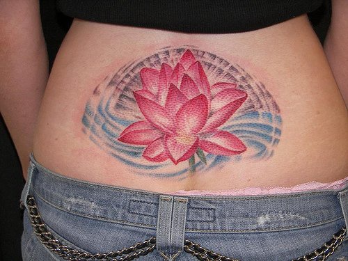 el tatuaje femenino de una flor de loto de color rojo hecho en la espalda