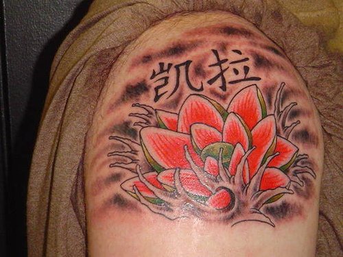 el tatuaje de una flor de loto roja con unos jeroglificos hecho en el hombro