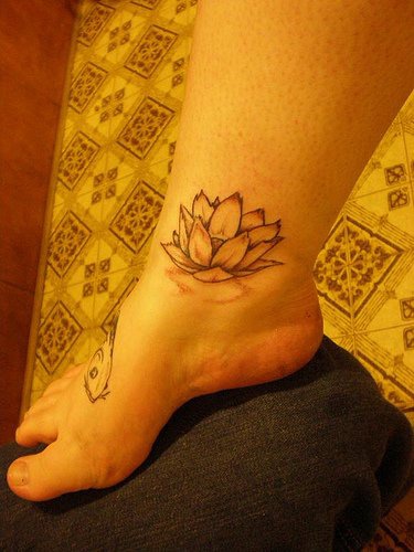 el tatuaje sencillo de una flor de loto en color negro en la pierna