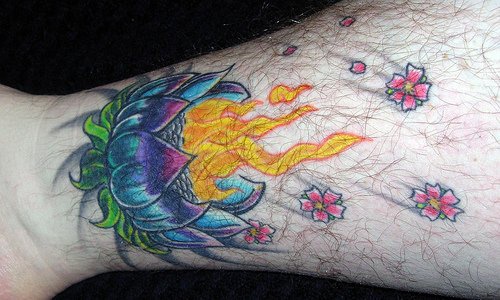 el tatuaje de muchos colores de una flor de loto con fuego hecho en la pierna