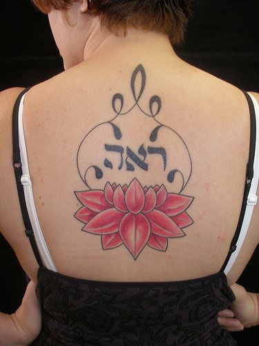 el tatuaje de una flor de loto grande de color rojo con una mantra el la espalda