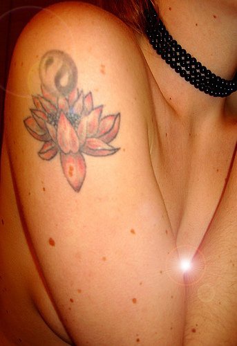 el tatuaje de una flor de loto con el simbolo de yin yang hecho en el hombro