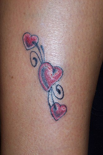 el tatuaje pequeño de tres corazones rojos en una traceria