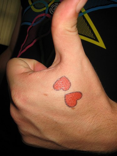 Two red hearts tattoo on hand