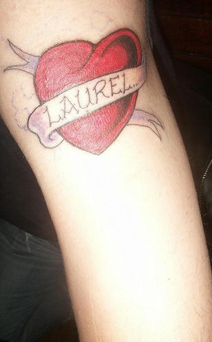 el tatuaje de un nombre sobre un corazon rojo hecho en la mano