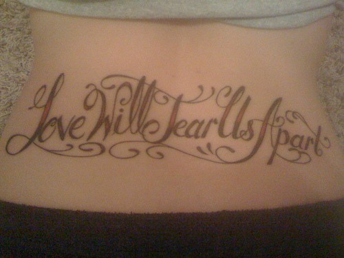 el tatuaje de la frase &quotlove will tear us apart" &quotel amor nos destrozara" en la espalda