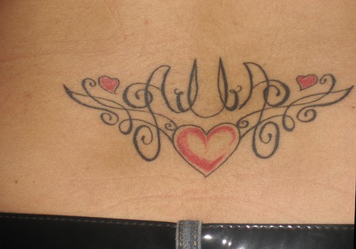 el tatuaje simetrico con una palabra y una traceria con corazones hecho en la espalda