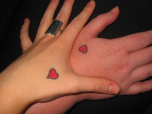 el tatuaje para pareja de dos corazones rojos pequeños hechos en las manos