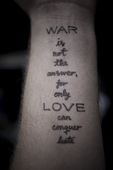el tatuaje de un texto sobre la guerra y el amor hecho en cursivo en la mano