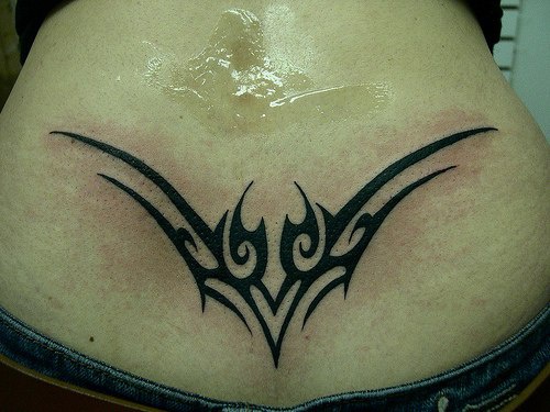 Lower back tattoo, sharp, designed pattern curled