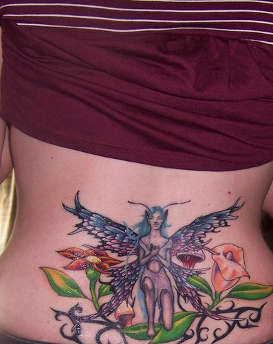 Lower back tattoo, blue, winged  devil fairy,in fine orchids