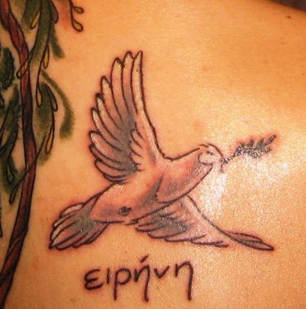 Lower back tattoo, bird flying and bearing a plant, named