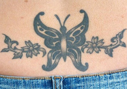 Tattoo am Becken von schönem Schmetterling  mit Blumen in Schwarz