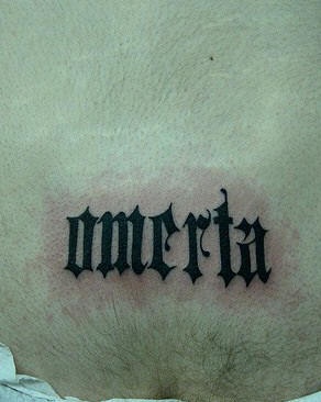Lower back tattoo,omerta  styled, black inscription