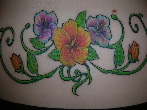 Lower back tattoo, picturesque, big, yellow and violet flowers